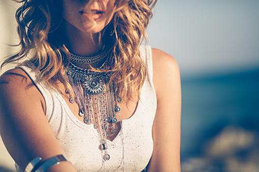 Close-up of young woman in boho style wearing stylish silver neklaces and arm cuff