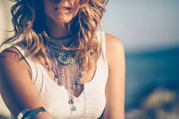 Close-up of young woman in boho style wearing stylish silver neklaces and arm cuff