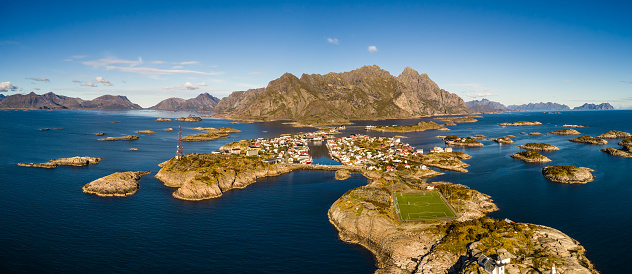 Aerial view of Henningsvaer, its scenic football field and mountains in the background. Henningsvaer is a fishing village located on several small islands in the Lofoten archipelago in Norway.