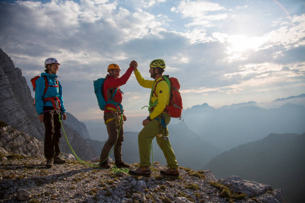 istock Climbers giving high fives on mountain summit 886635628