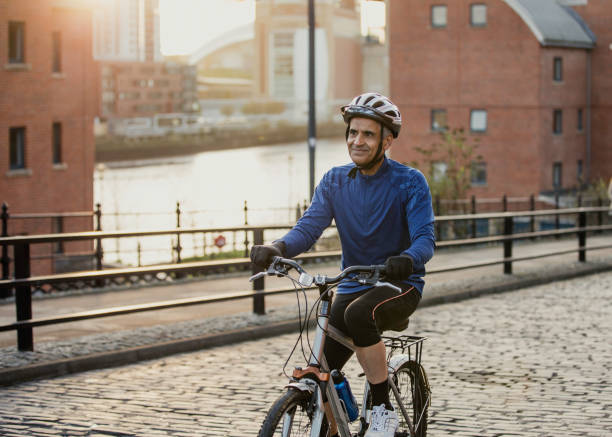 A Senior Man on His Street Bike A senior man riding his bicycle in an urban location over cobblestones man 60s bicycle stock pictures, royalty-free photos & images