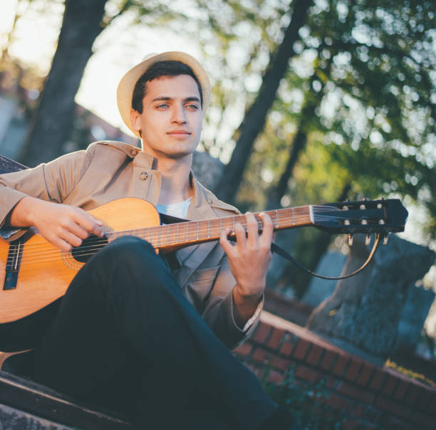 istock Young man playing guitar on park bench 886635710