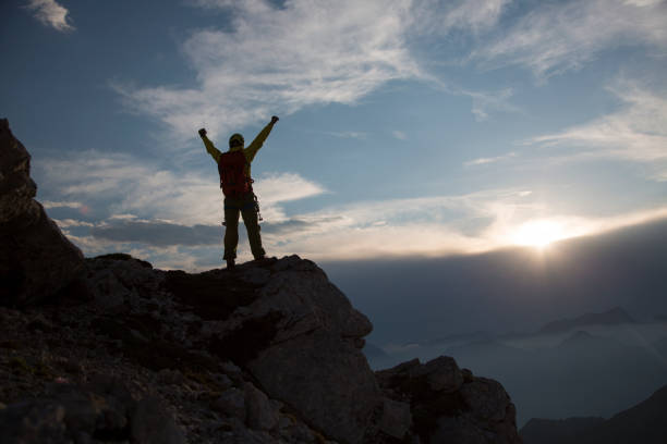 istock Hiker standing with raised arms on mountain 886635782