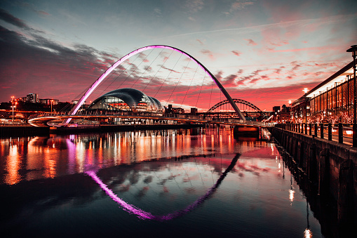 A view of the Millennium bridge at sunset with the Tyne Bridge in the background, warm toned