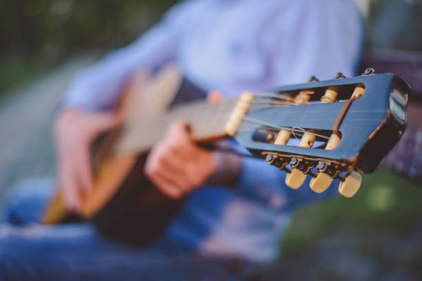istock Young man playing guitar on park bench 886636440