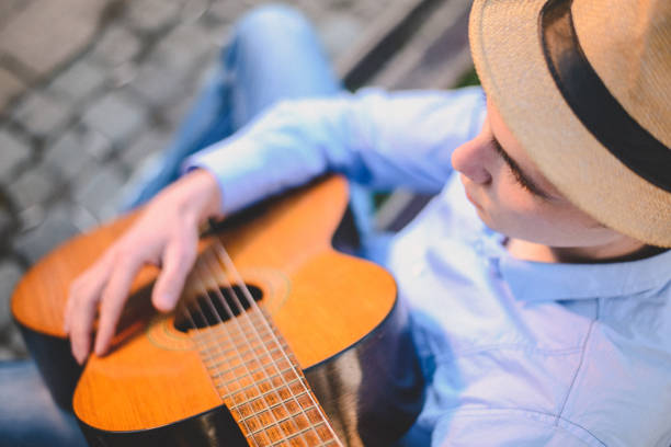 istock Young man playing guitar on park bench 886636518