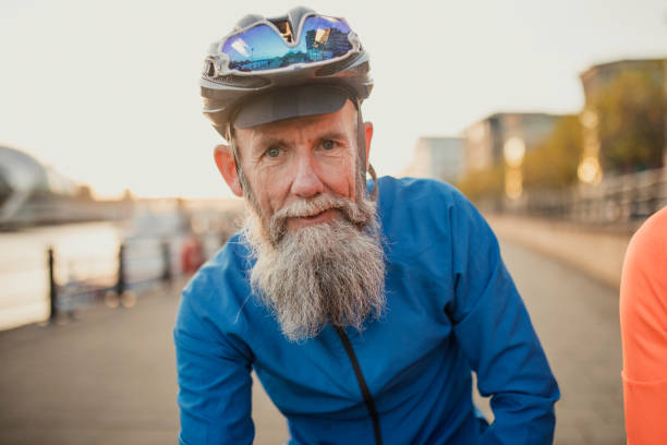 Portrait of Older Man with Beard An older man with a beard, standing in cycle clothes next to the river Tyne man 60s bicycle stock pictures, royalty-free photos & images