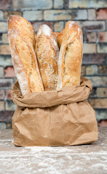 the fresh baked rustic bread loaves in paper bags the fresh baked rustic bread loaves in paper bags bread bakery baguette french culture stock pictures, royalty-free photos & images