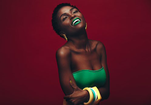 Beautiful african woman with vivid makeup. Beauty portrait of sensual model with colorful makeup on red background.