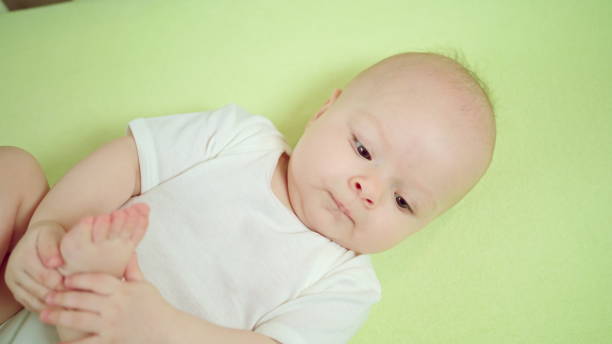 istock Baby Lying in a Crib at Home Eating its Toes 886639254