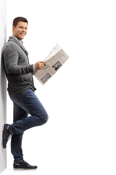 istock Guy with a newspaper leaning against a wall 886640098