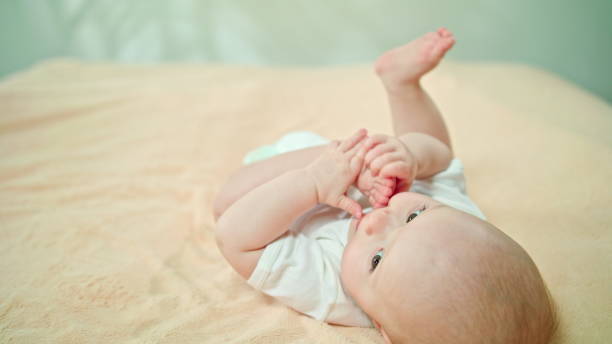 istock Baby Lying in Bed at Home Eating its Foot 886643136