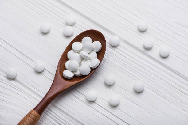istock white medical pills on wooden spoon 886643178
