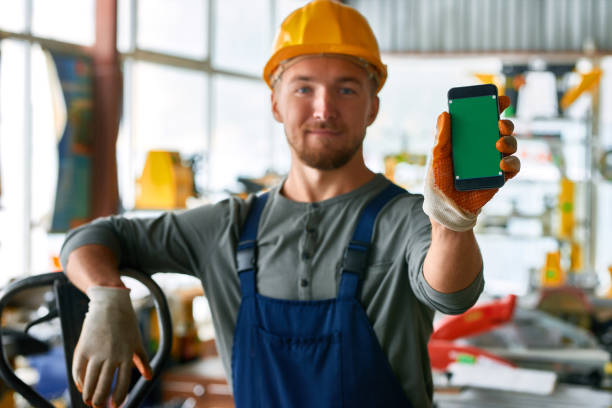 young workman presenting mobile app - manual worker portrait helmet technology imagens e fotografias de stock