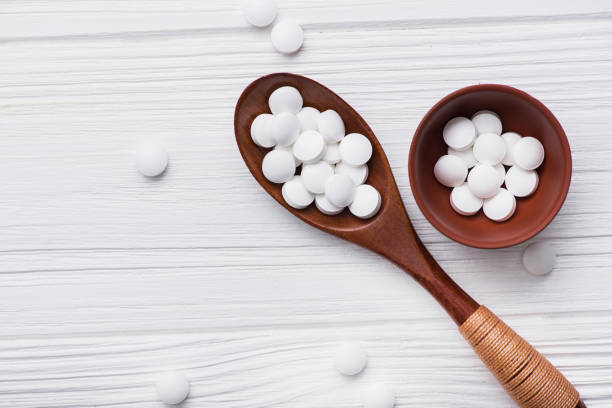 istock white medical pills on wooden spoon 886643398
