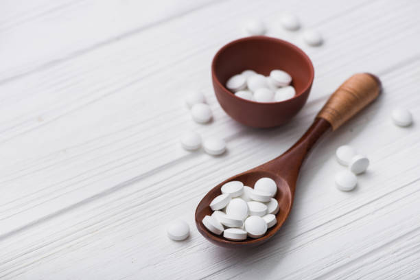 istock white medical pills on wooden spoon 886643488
