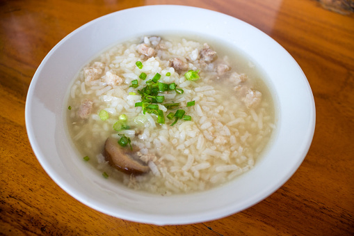 Minced pork rice soup in white bowl on wooden background
