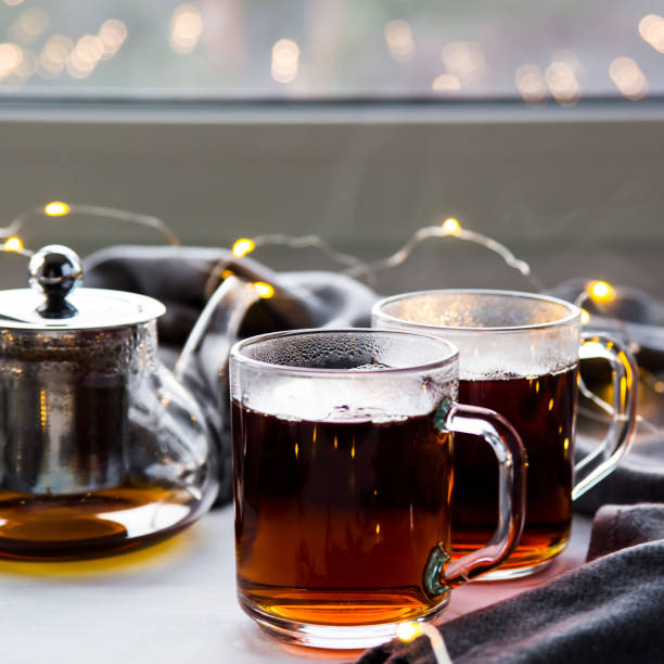 té negro en un vaso de agua transparente y las tazas por la ventana. concepto de invierno - texas tea fotografías e imágenes de stock