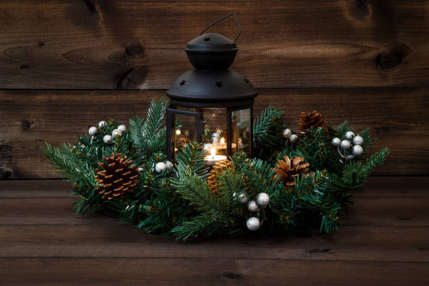 istock Decorated Advent wreath with a black lantern with a burning tea light and open door on a wooden background 886658092