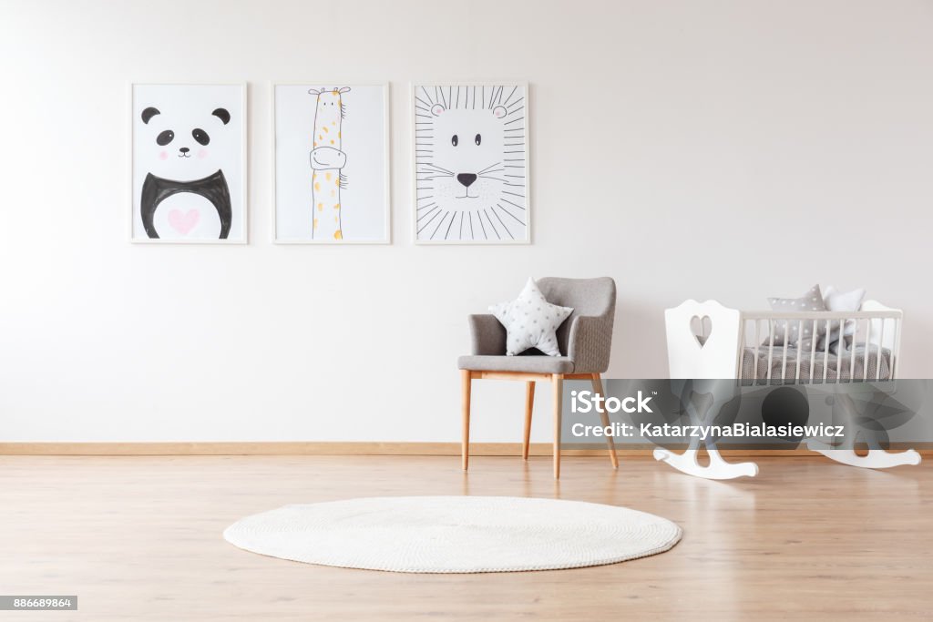 White crib in baby's room Grey chair with pillow and white round carpet near white crib in baby's room with animal posters on wall Child Stock Photo