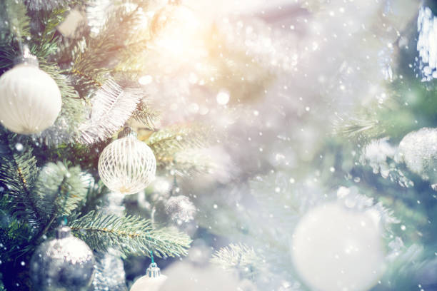 istock White and silver bauble hanging from a decorated Christmas tree with background. 886697254