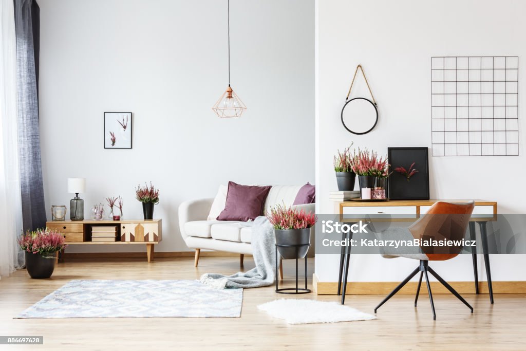 Workspace in bright living room Mockup of round plate on wall and designer chair at desk with heathers in bright living room with workspace Living Room Stock Photo