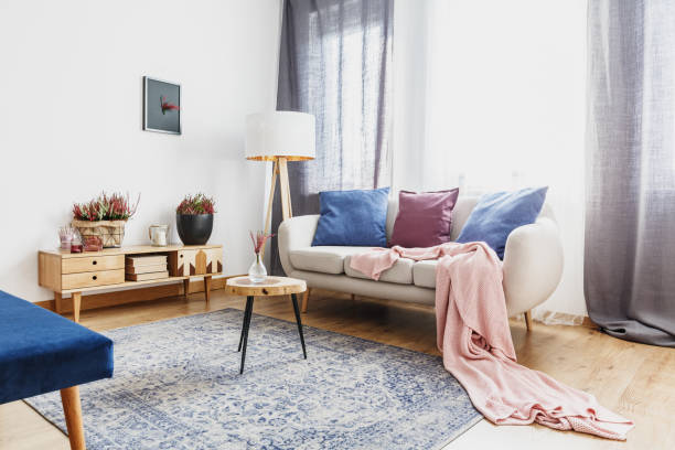 Living room with rustic cupboard Wooden stool with glass vase on patterned carpet next to sofa with pink blanket in cozy living room with rustic cupboard leather cushion stock pictures, royalty-free photos & images