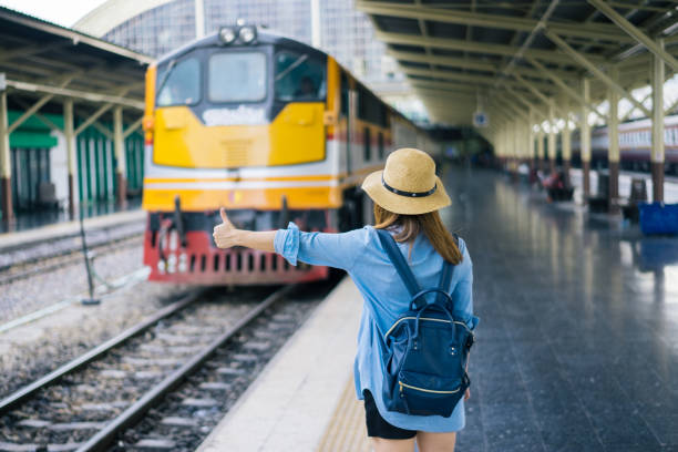 istock Young woman traveler with sky blue backpack and hat looking the map with train background at train station Bangkok. Traveling in Bangkok Thailand. Travel concept 886697664