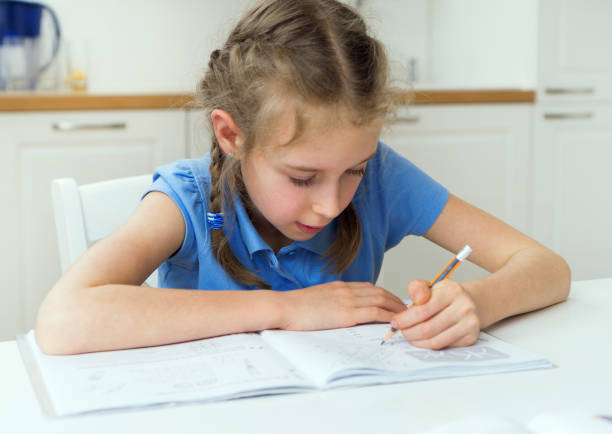istock Little girl doing her homework at home. 886698174