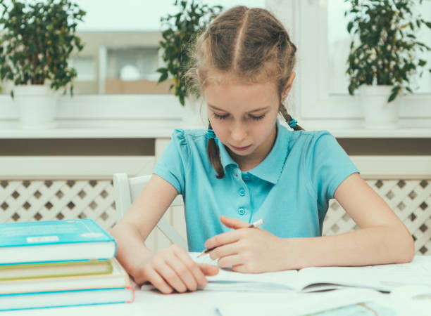 istock Little girl doing her homework at home. 886698236