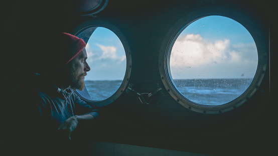 Hombre en la ventana ojo de buey de un barco en un mar photo