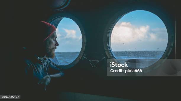 Man At The Porthole Window Of A Vessel In A Rough Sea Stock Photo - Download Image Now