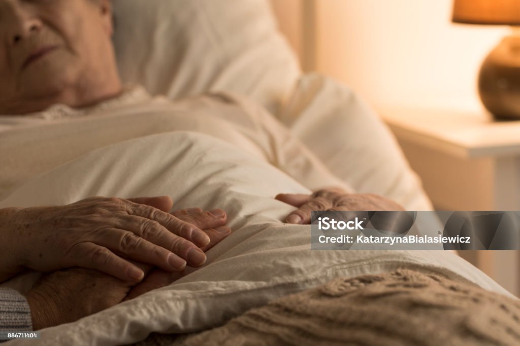 Support during sickness Close-up of hand of senior on hand of dying elderly person as sign of support during sickness Bed - Furniture Stock Photo