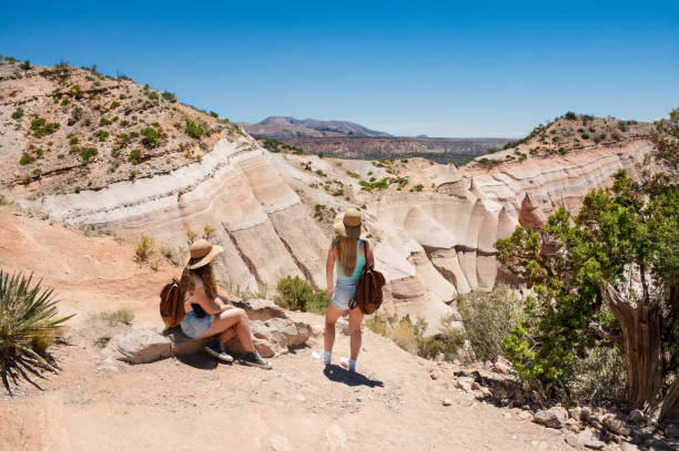 Girs enjoying view on hiking trip in beautiful mountains. Friends looking at  beautiful view on hiking trip in the mountains. Kasha-Katuwe Tent Rocks National Monument, Close to  Santa Fe, New Mexico, USA santa fe new mexico stock pictures, royalty-free photos & images