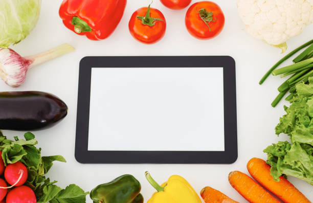 istock Touch screen digital tablet, fresh vegetables and grass on a white wooden table, food and gardening app concept. 886725384