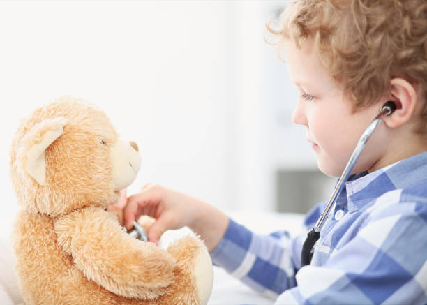 istock Child Doctor Checking a Teddy Bear's Heartbeat. 886732098