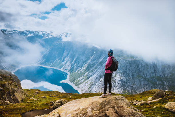 istock Young woman with backpack standing on fjord coast 886761664