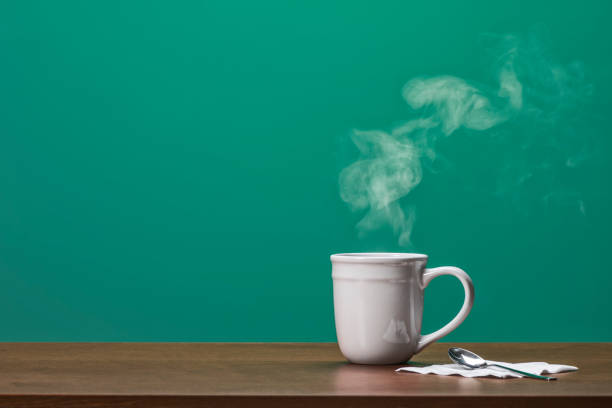 Large white mug with a steamy hot coffee or tea on a wooden table