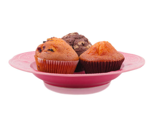 istock Three cupcakes in a plate on a white isolated background. Side view 886782028
