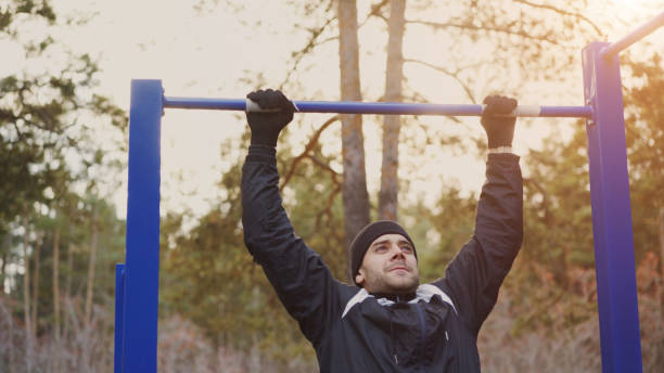 istock Young athletic man doing pull-up exercise in winter park outdoors 886783124