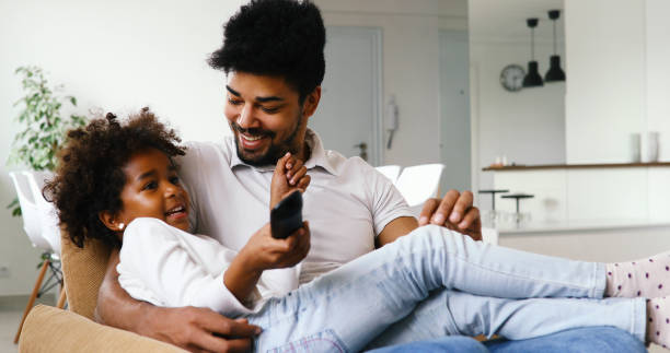 istock Father and daughter sitting on couch at home 886786380