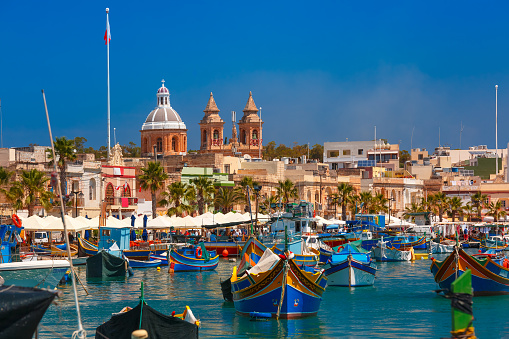 Traditional eyed colorful boats Luzzu in the Harbor of Mediterranean fishing village Marsaxlokk, Malta