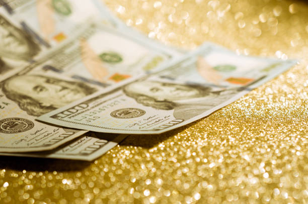 The dollars banknotes on gold glitter background represent the concept of wealth and investment success.