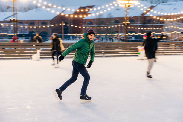 istock Joyful bearded man practices going skating on ice ring, has cheerful expression, smiles happily, demontrates his professionalism. Active sporty male in green jacket go in for winter sport 886791420