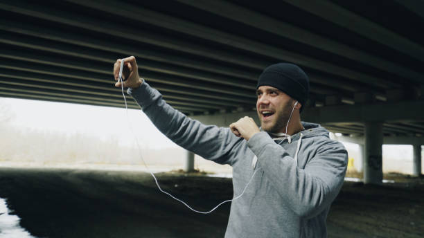 istock Athlete man having video chat on smartphone with his trainer after workout at urban location outdoors in winter 886797604
