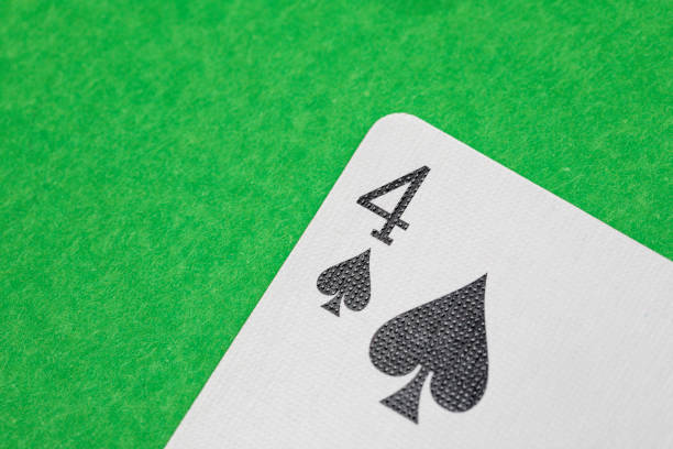 Close up shot of a playing card on a green surface, four of spades