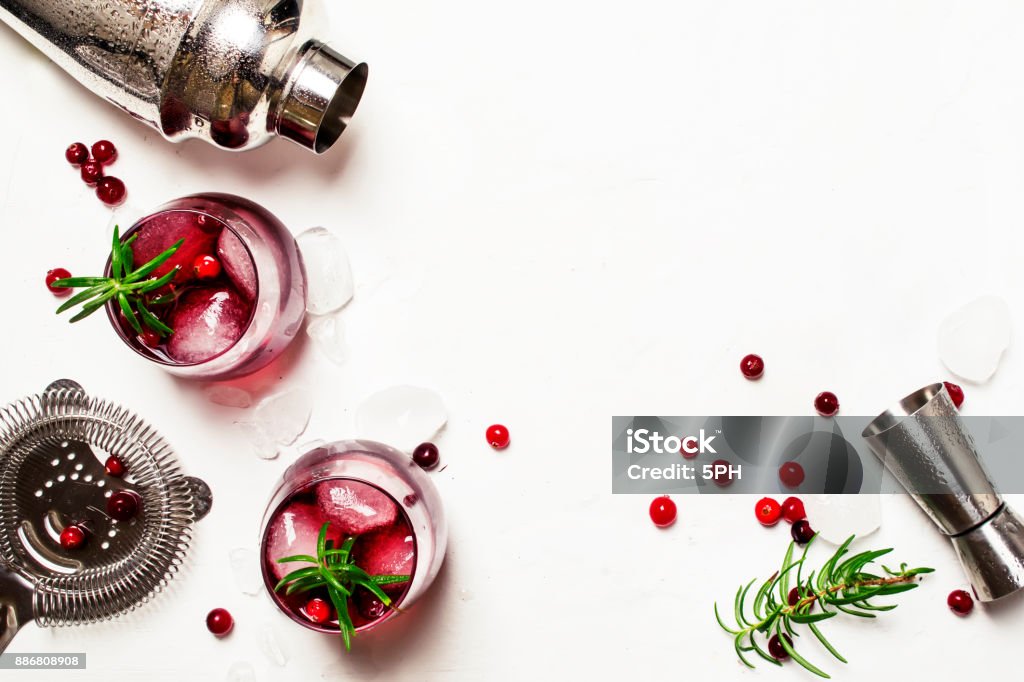 Red cranberry cocktail with ice, rosemary and vodka Red cranberry cocktail with ice, rosemary and vodka, bar tools, white background, top view Cocktail Stock Photo