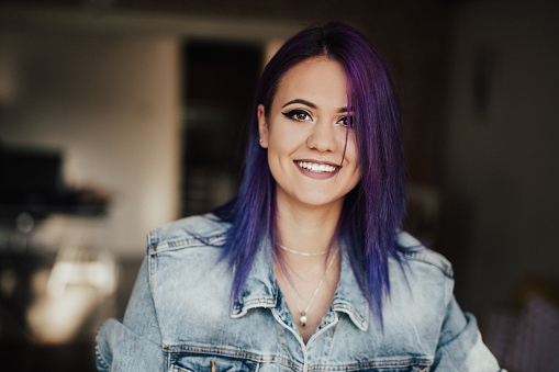 Happy smiling hipster girl with purple hair looking at camera