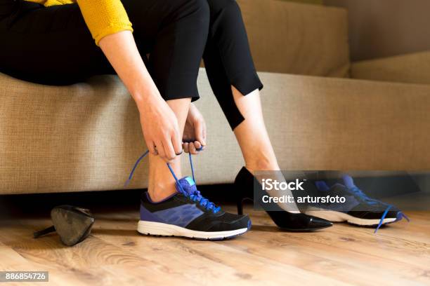 Photo libre de droit de Changements Talons Femme Chaussures De Bureau Après Une Journée De Travail En Position Assise Sur Le Canapé Prêt À Se Promener Ou Courir banque d'images et plus d'images libres de droit de Chaussures