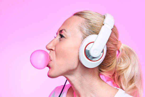 blondynka nadmuchuje gumę bąbelkową na różowym tle - chewing gum audio zdjęcia i obrazy z banku zdjęć